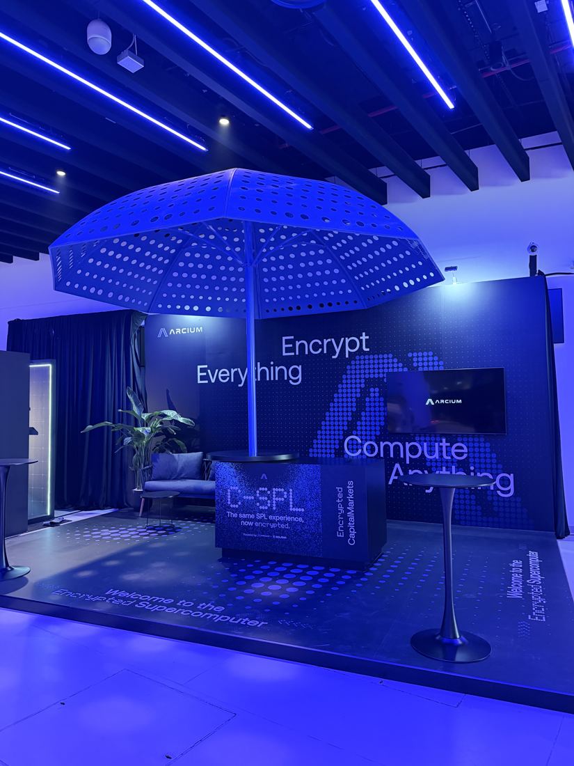 Arcium booth with a large perforated umbrella and 'Encrypt Everything, Compute Anything' wall